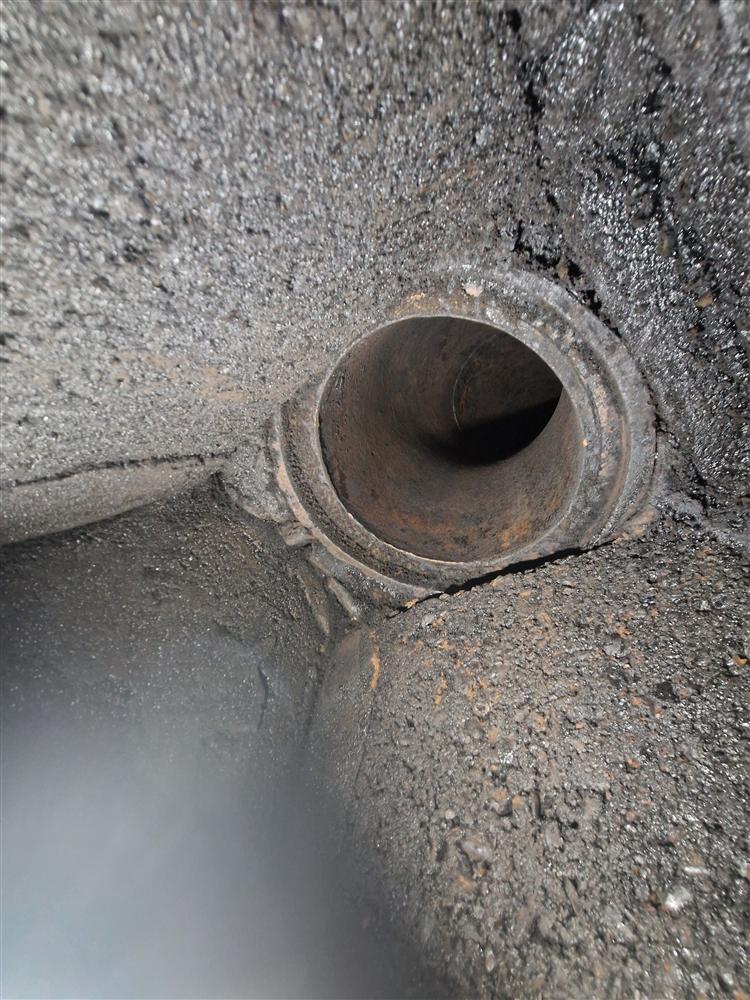 Close-up of glazed tar around a flue pipe joint inside a chimney